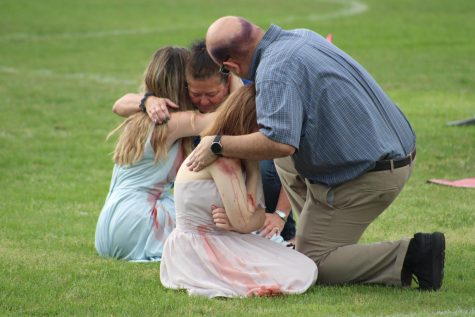The photo illustrates the staff John Scott, and Michell herring comforting actors who attend River Ridge High School, during the enactment of prom promise.  